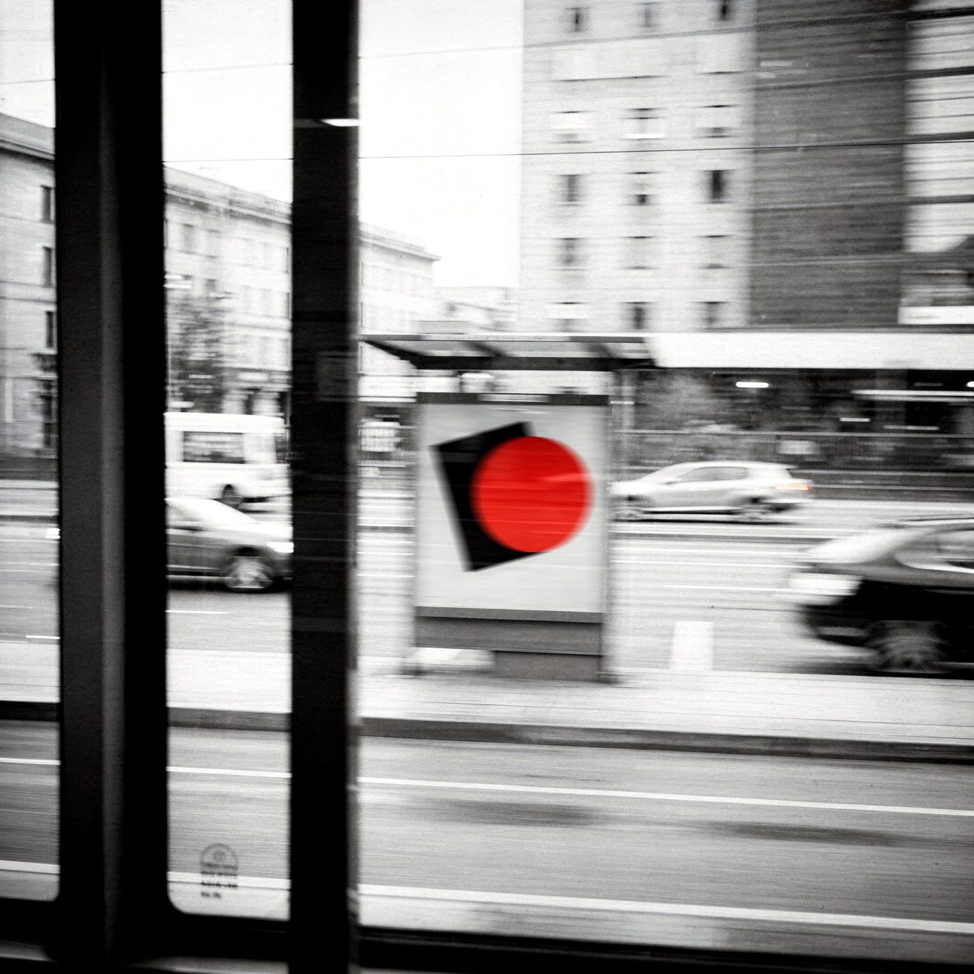 Manifesto con un cerchio rosso visto dal finestrino di un tram in corsa, città in bianco e nero mossa
